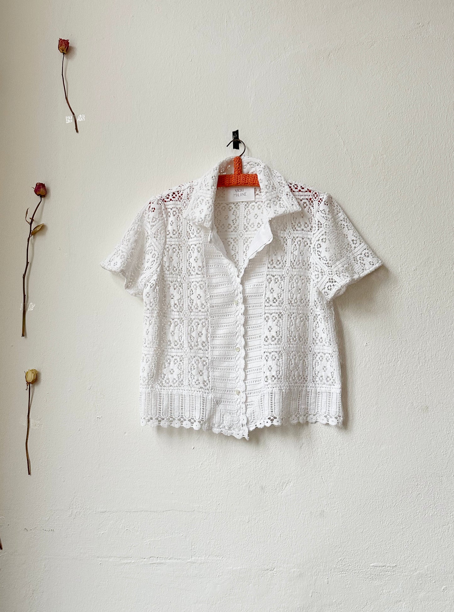 Short sleeve lace blouse hangs on the wall. 