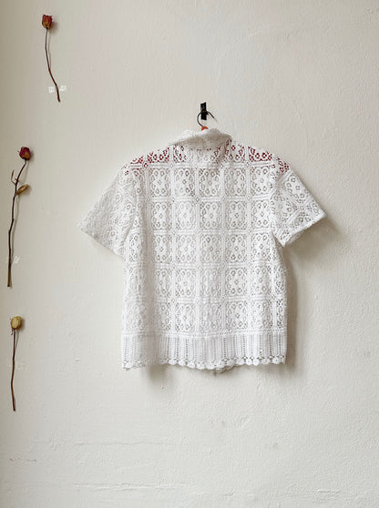 Back view of a short sleeve lace blouse hanging on the wall