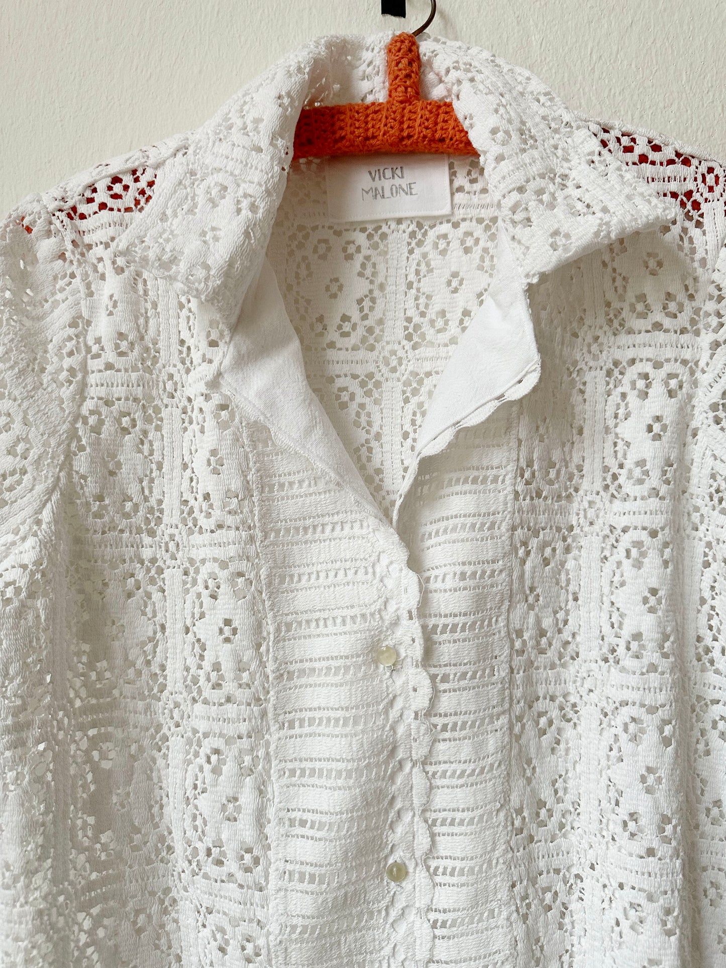 Front detail view of white lace blouse. 