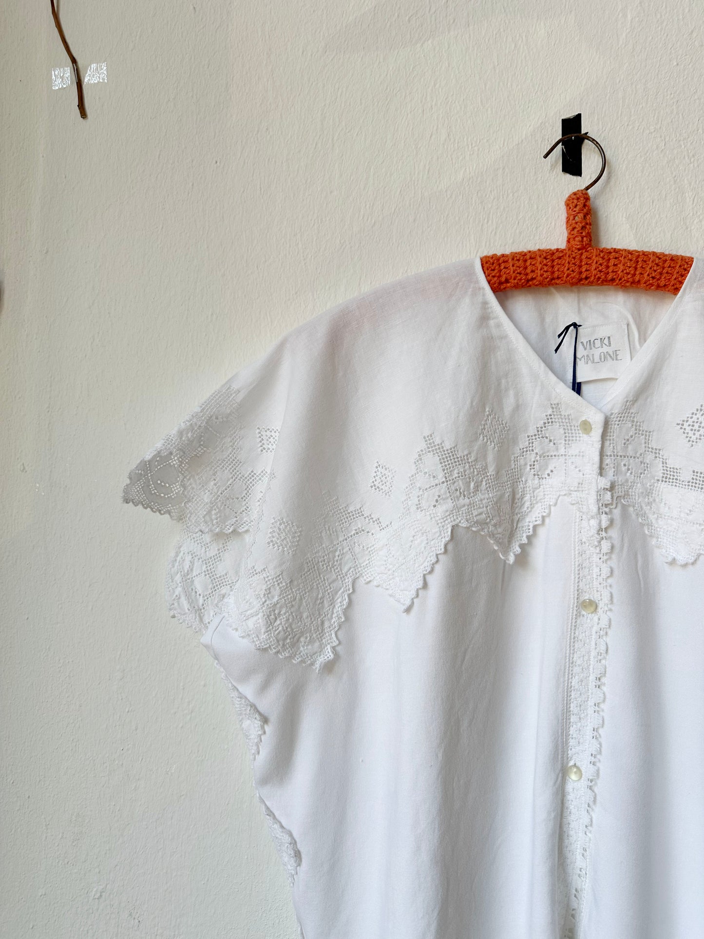 Detail view of white blouse with scalloped lace trim 