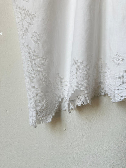 Detail view of lace trim of white blouse. 